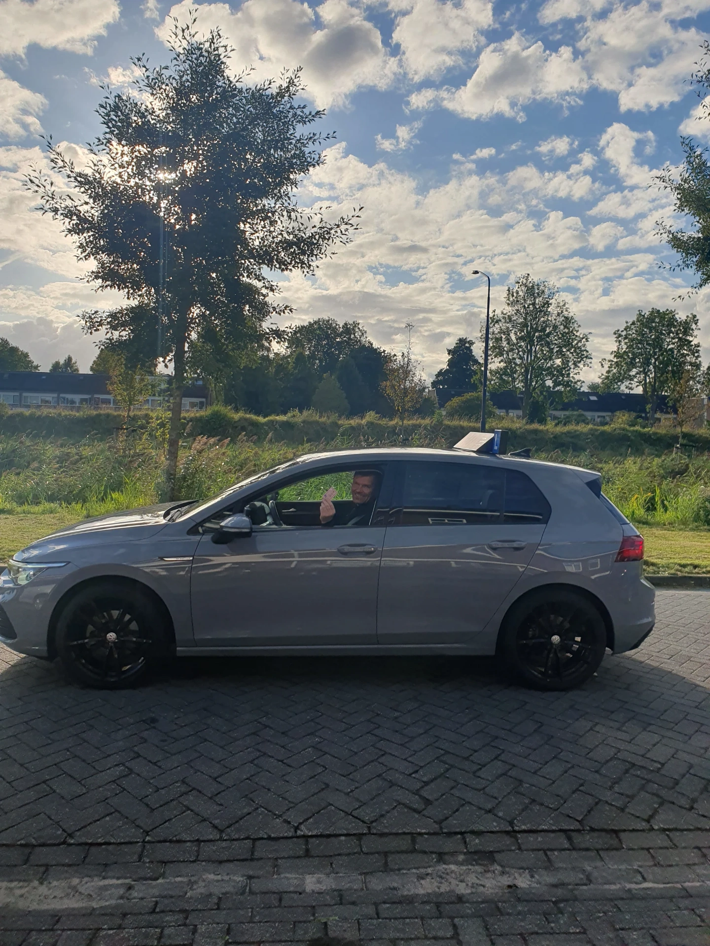 Lachende leerling zwaait vanuit de lesauto van GOAT on the Road